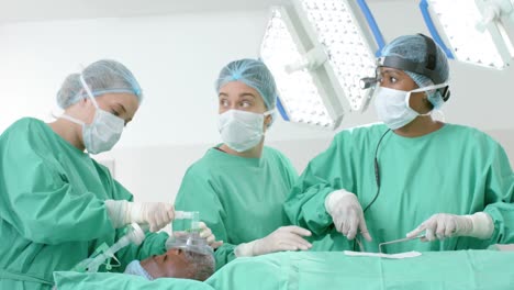 diversos cirujanos con batas quirúrgicas operando a un paciente en el quirófano, cámara lenta