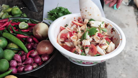 Handheld-shot-Chef´s-hands-mixing-delicious-colorful-squid-salad-on-white-bowl