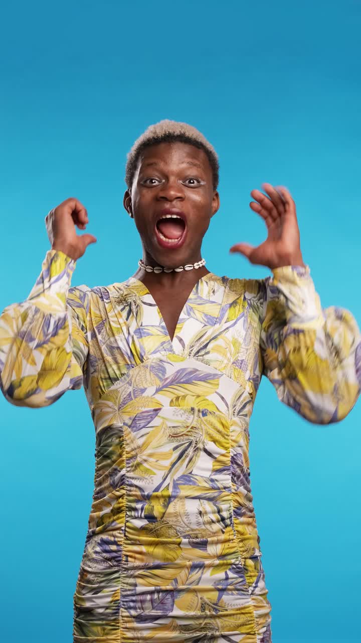Excited black androgynous model in dress screaming on blue
