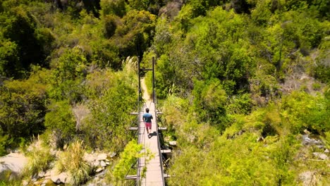 vista aérea siguiendo a un tipo en un puente en el parque nacional río clarillo en santiago de chile en un día soleado