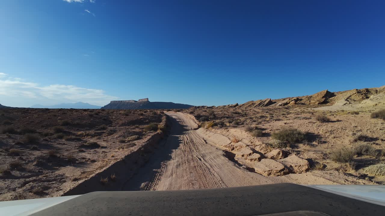 vista de ojo de avión no tripulado capturando a un hombre fuera de carretera en un camino de arena desde una perspectiva de vista frontal se embarca en un brillante viaje empapado de sol a lo largo de los senderos de la carretera