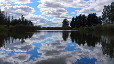 Blaues-Seewasser,-Spiegelreflexion,-Heller-Malerischer-Bewölkter-Himmel,-Ruhige-Szene