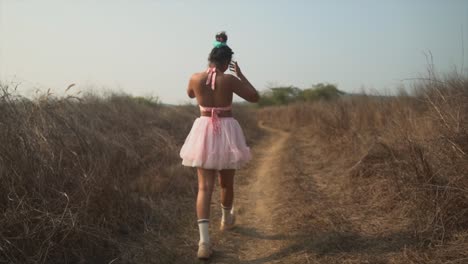 trendy looking girl walking in a pink skirt, elegant outfit, sun is shining