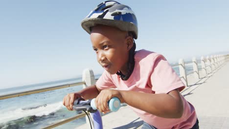 Video-of-happy-african-american-boy-riding-scooter-by-sea