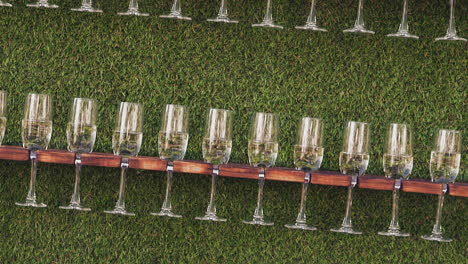 glasses with champagne on wooden racks near artificial grass