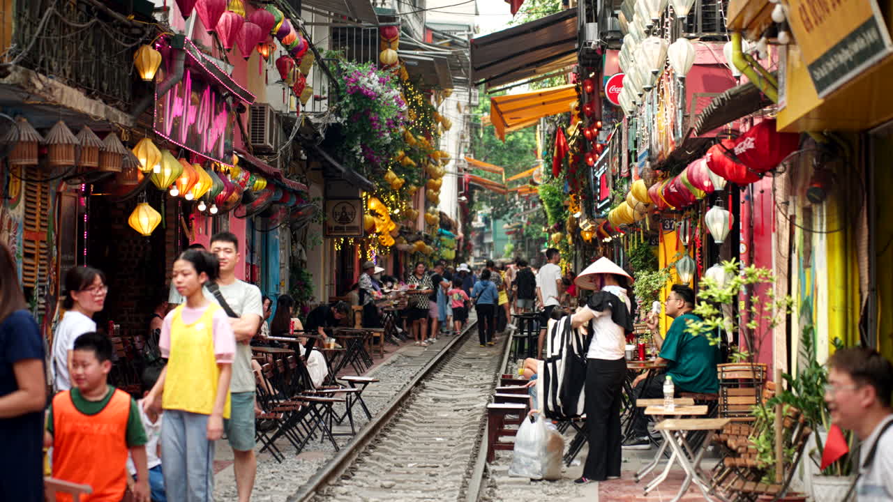 Crowd of people on Hanoi famous train street with cafes and shops around, Establishing shot