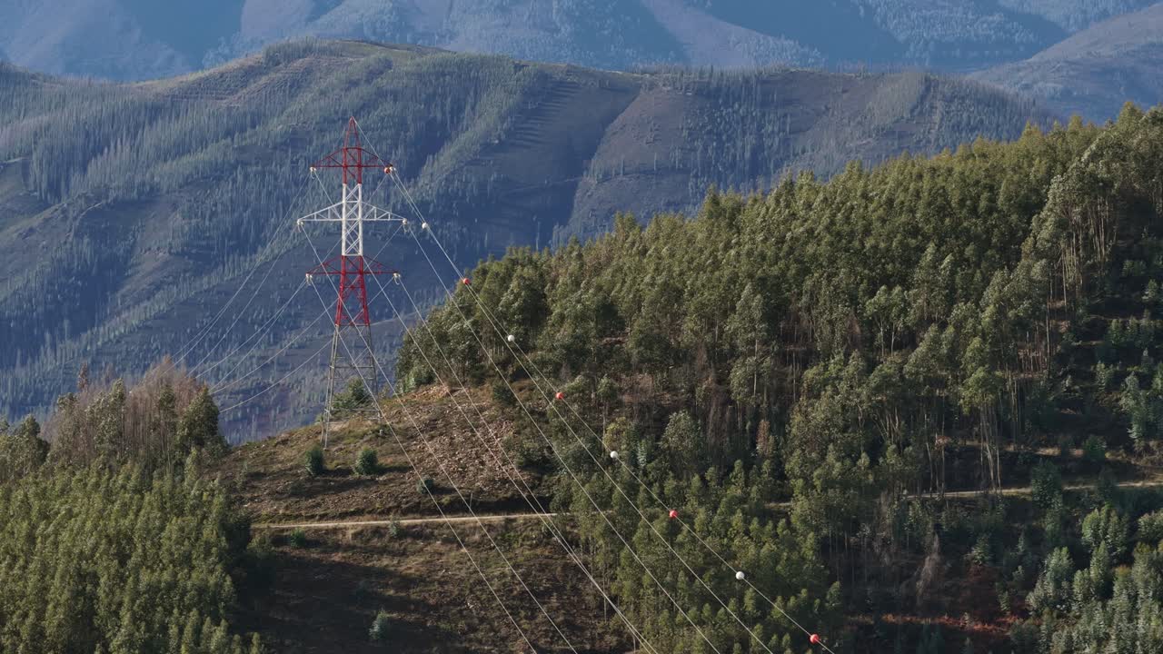 Elektrické vedení a stožáry nad horami a lesy, záběr s přiblížením 3