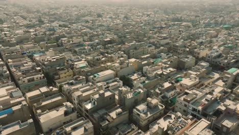 Aerial-drone-backward-moving-shot-over-congested-city-of-Ancholi-with-rows-of-buildings-in-the-residential-area-of-Karachi,-Pakistan-on-a-bright-sunny-day