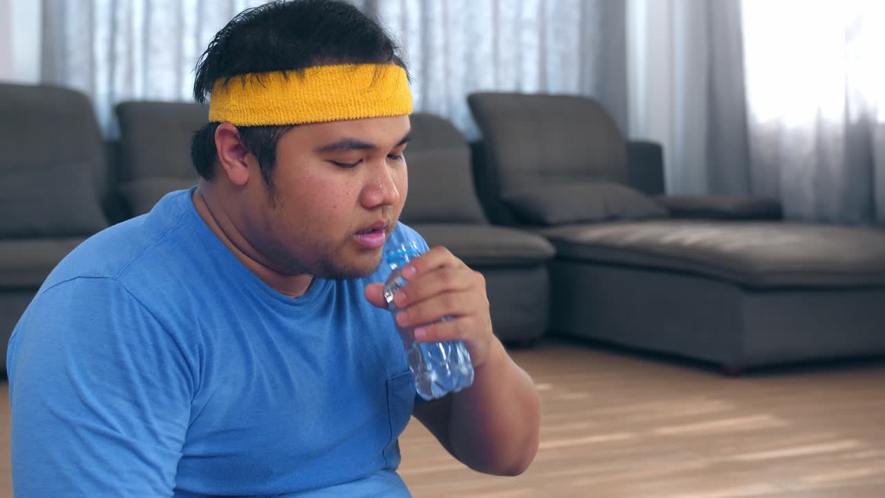 Fat Man Drinking Water After Exercises At Home