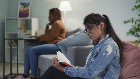 woman learns theory while girl friend doing tasks on laptop