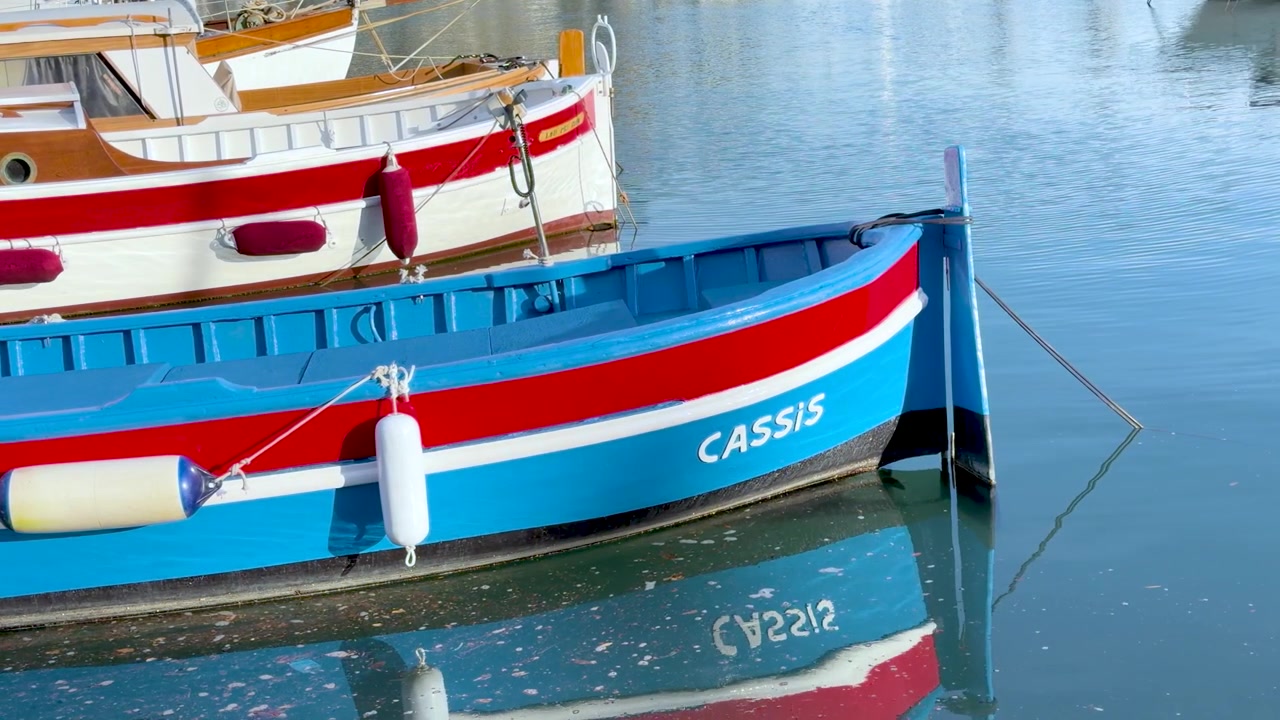 Barche da pesca in legno dai colori vivaci ondeggiano dolcemente nell'acqua limpida del porto di Cassis.
