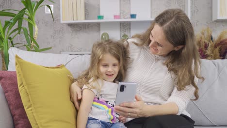 Mother-and-daughter-looking-at-the-phone-at-home.