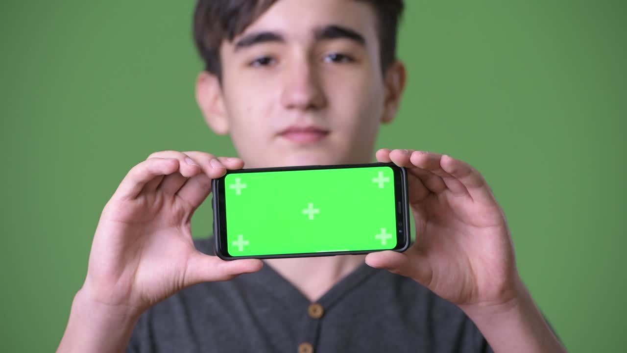 초록색 배경에 젊은 잘생긴 이란 십대 소년