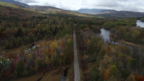 Flying-over-scenic-autumn-forest-landscape-with-railway-and-river-aside