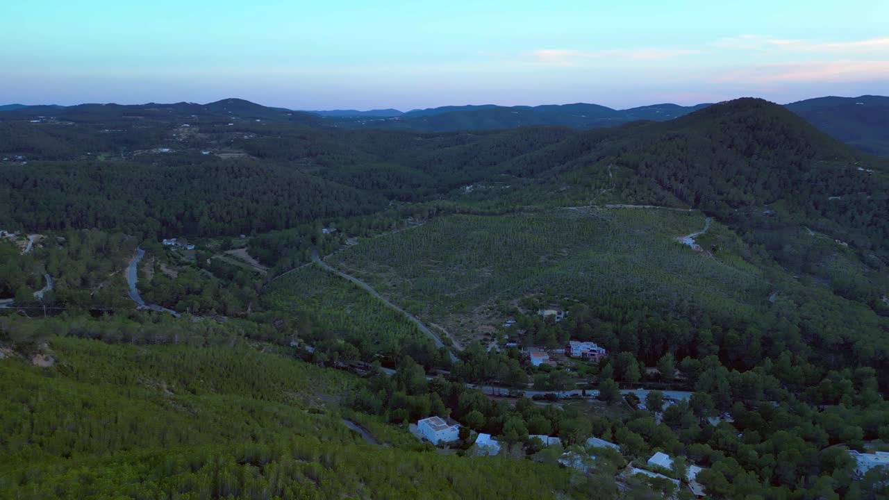 panoramic view of Cala Benirras bay and wooded hills at dusk in Ibiza. Nice aerial view flight rotation pan to right drone