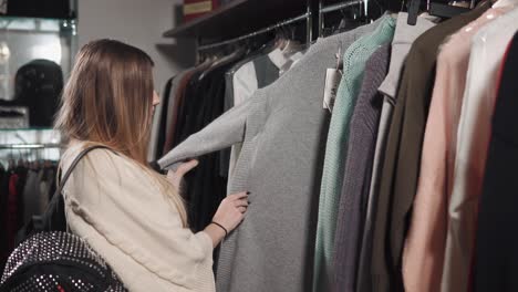 woman shopping for sweaters in a clothing store