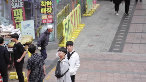 street scene in south korea, with a man pushing a cart full of recyclables