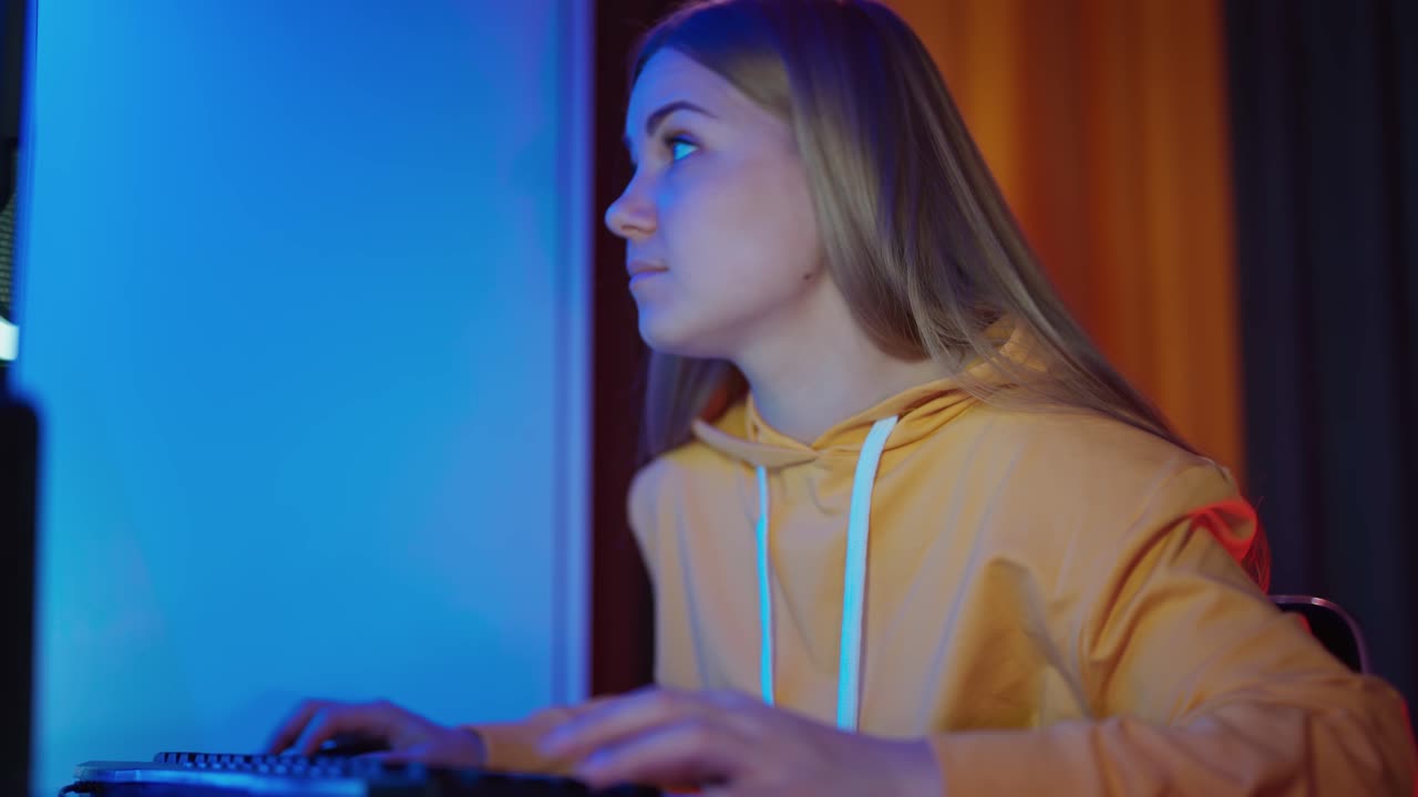 Pretty girl in casual clothes looking at the screen. Smiling young woman playing on a computer at home.