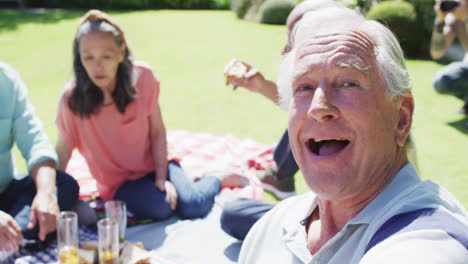 Glücklicher-älterer-Kaukasischer-Mann,-Der-Bei-Einem-Picknick-Mit-Verschiedenen-Freunden-Im-Sonnigen-Garten-Lacht,-Zeitlupe