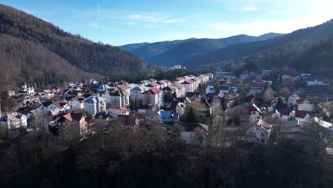 vuelo aéreo hacia adelante sobre la ciudad de sinaia entre montañas verdes de rumania durante el día soleado