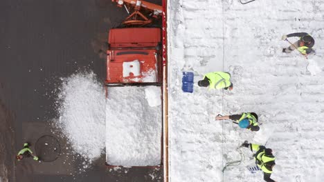 man wearing high visibility jacket and harness clearing roof of snow with shovel