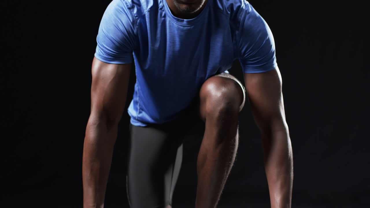 African American athlete in starting position on a black background
