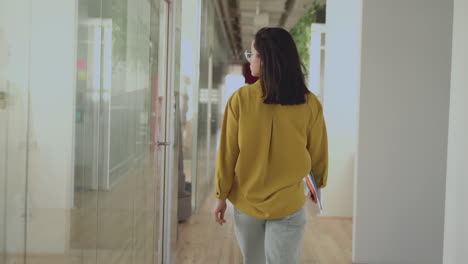 International-Women's-Day.-Business-female-walking-in-a-corridor.-Back-to-the-camera.