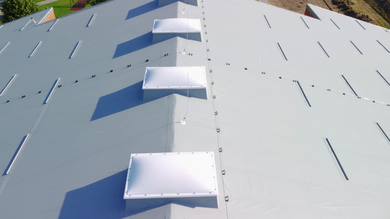 grandes cúpulas de luz de plástico blanco en la parte superior del techo aislado gris y parque infantil frente al edificio