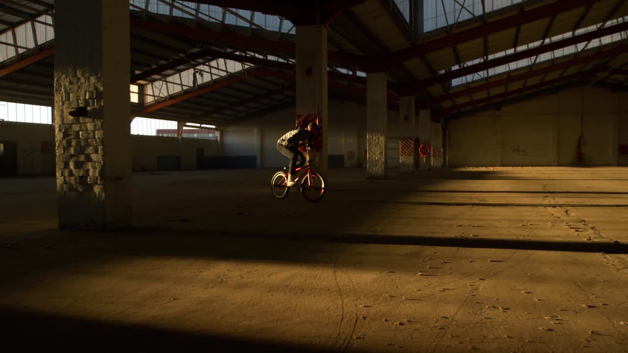 Ciclista BMX in un magazzino vuoto.
