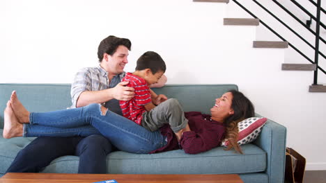 Parents-Lying-On-Sofa-And-Playing-With-Children-At-Home