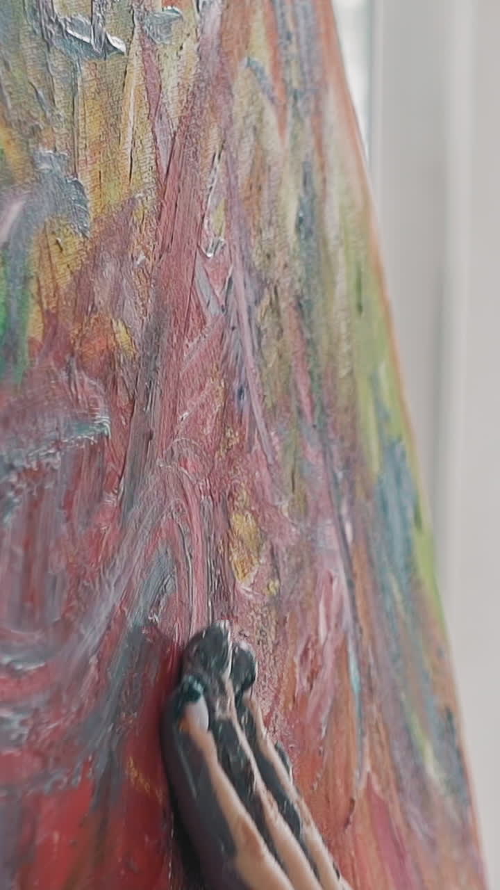 Talented woman artist at work on colorful abstract painting making strokes by palm on canvas in studio slow motion extreme close side view