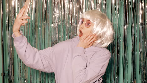 woman taking a selfie with a wig, sunglasses and a purple hoodie