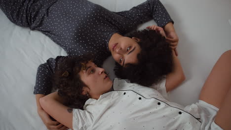 una pareja feliz hablando en la cama.