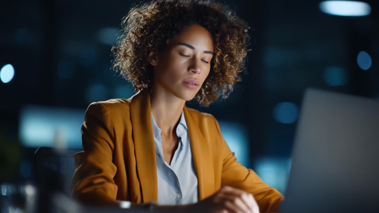 Focused Professional Woman Working Late at Night, Engaged in Computer Task Against a Softly Lit Modern Office Background