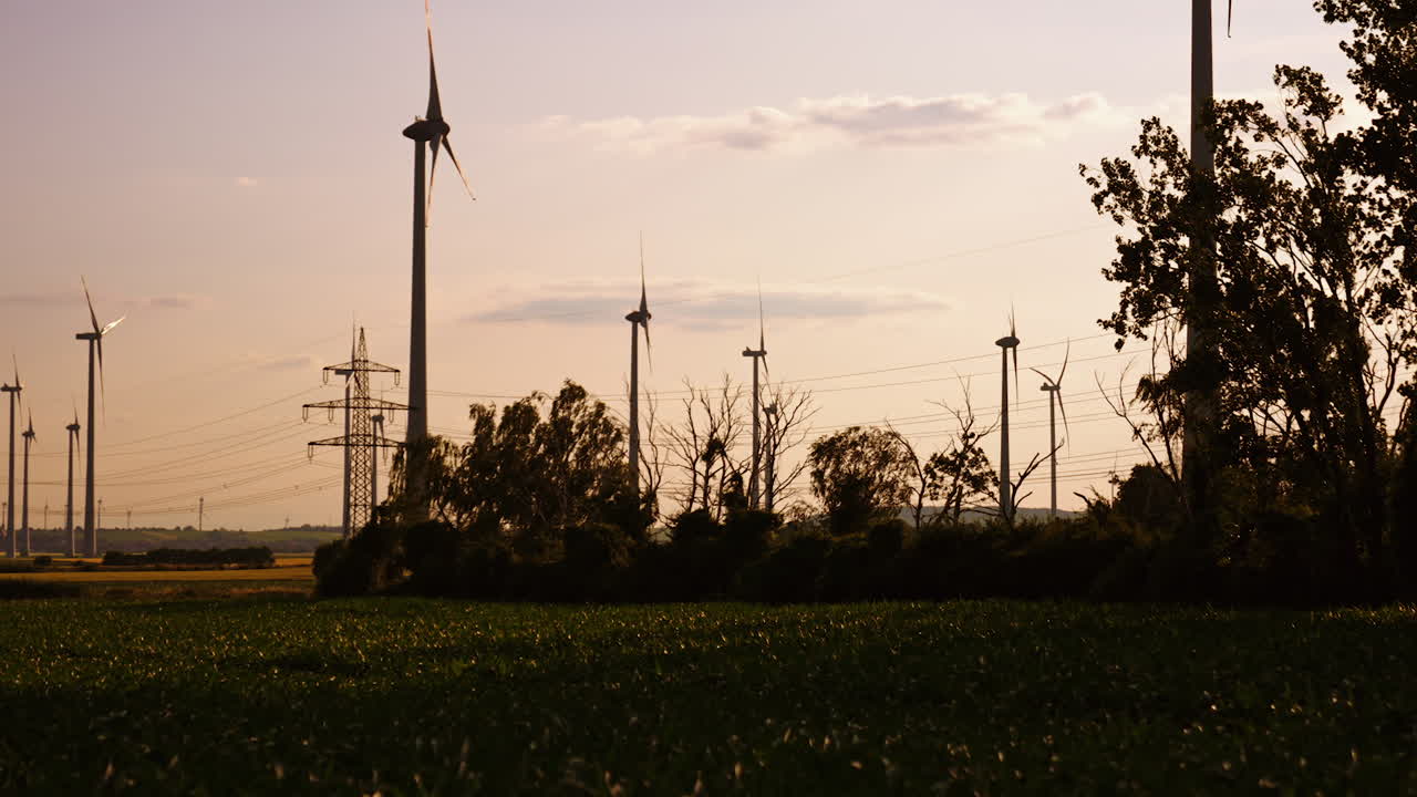 Tall wind turbines in golden fields. Wind turbines rise above the green landscape during sunset, creating a serene contrast with the colorful sky