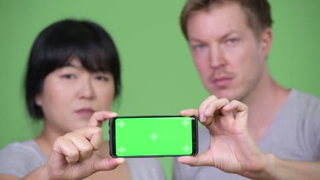 young happy multi-ethnic couple showing phone together