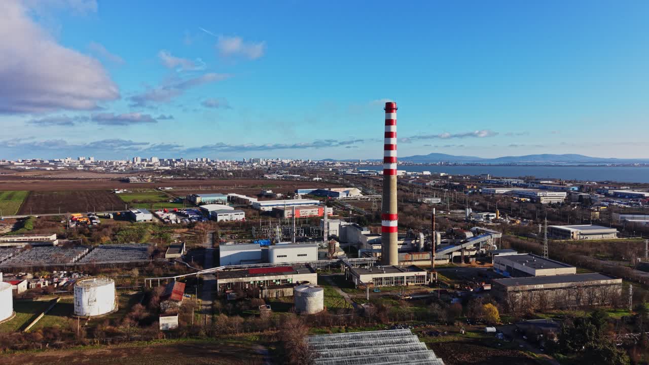Teollisuusalue savupiipun ja kaupungin siluetin kanssa taustalla