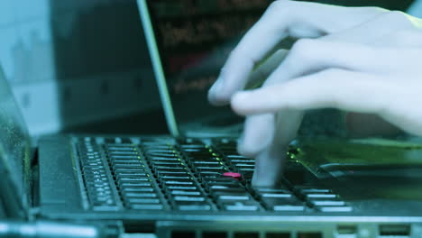 primo piano di un hacker irriconoscibile a tarda notte digitando sul computer portatile