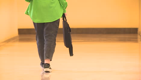 person walking down a corridor with a bag
