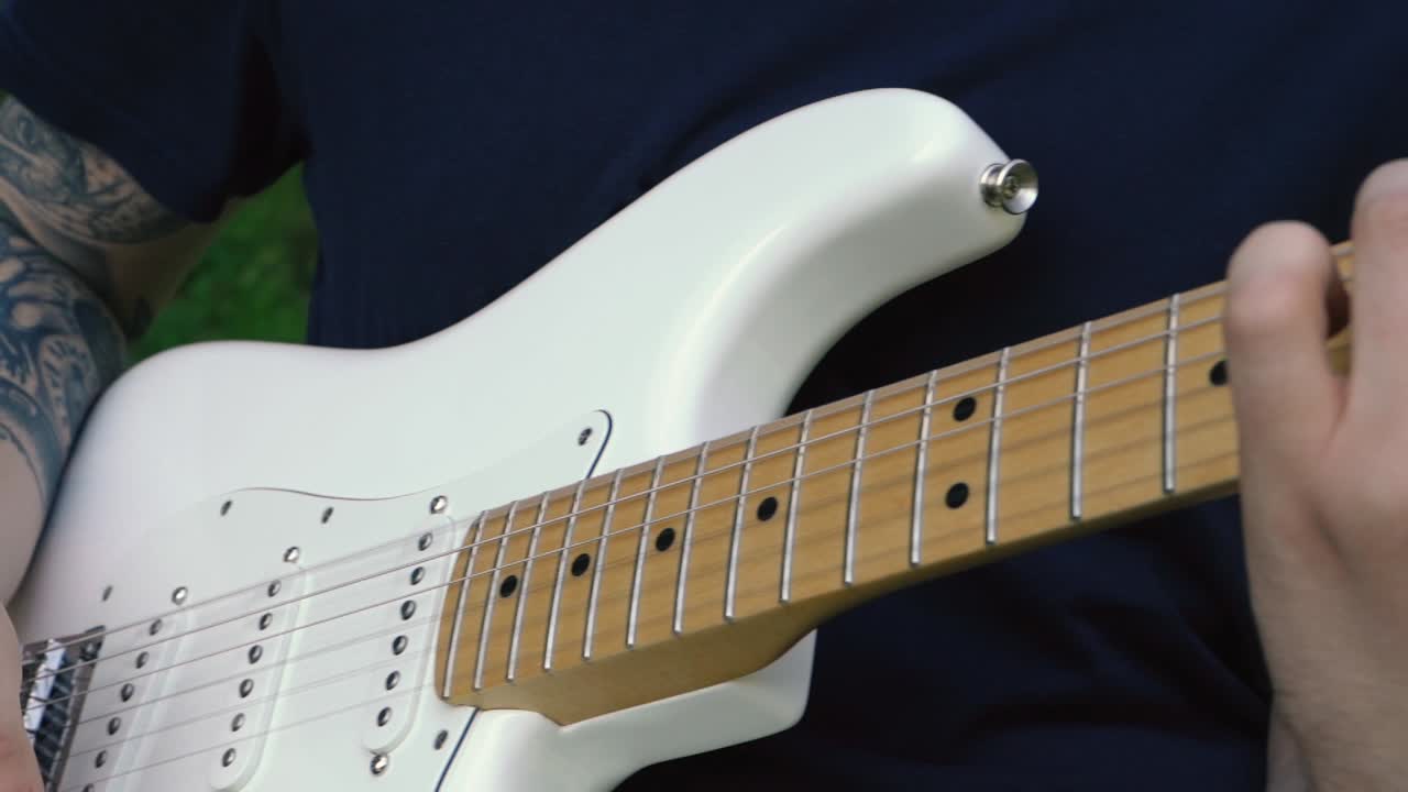 hombre tocando la guitarra frente a una hermosa cascada en islandia