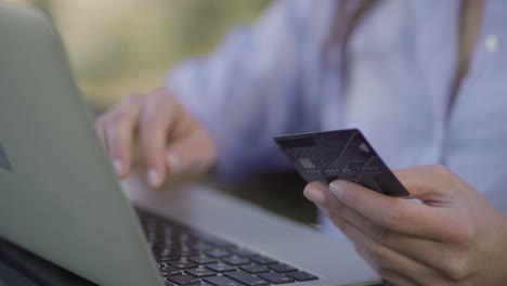 primer plano de manos femeninas pagando en línea con tarjeta de crédito en una computadora portátil