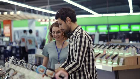 en la tienda de electrónica, una consultora da consejos profesionales a un joven que considera comprar un nuevo teléfono inteligente y