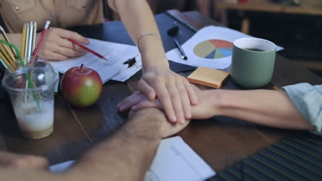 Business-people-teaming-together-putting-their-hands-on-each-other-on-table