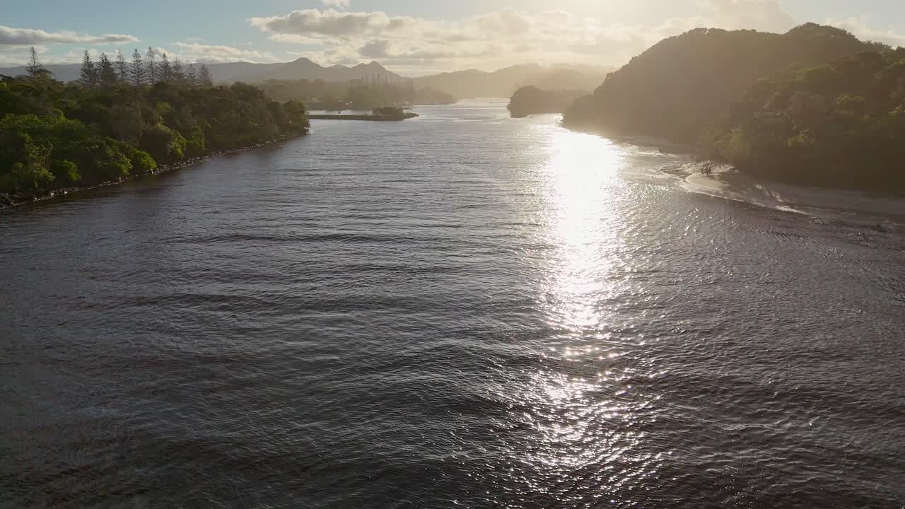 Drone captures serene river and landscape during sunset, highlighting tranquil waters and lush greenery