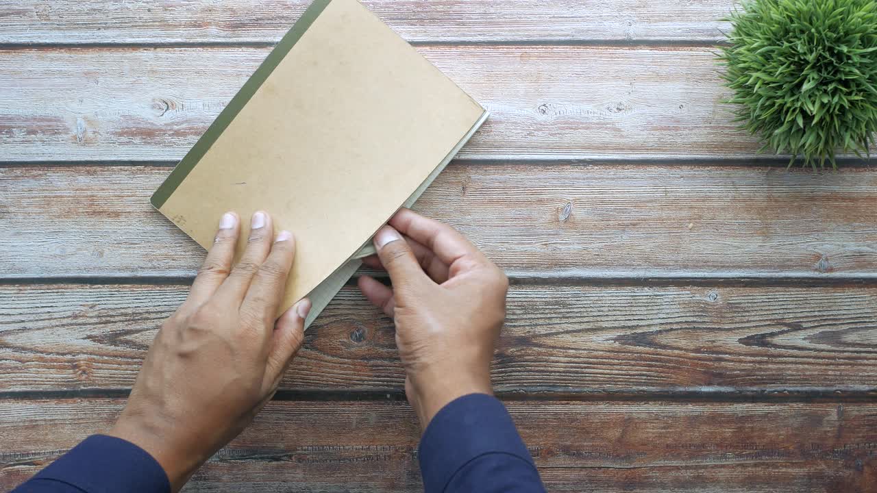 Hands holding a notebook and money on a wooden desk