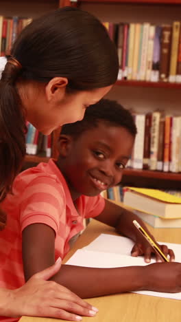 teacher helping pupil and smiling at camera