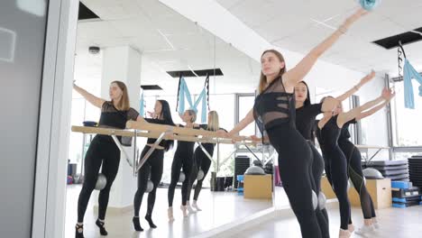 women doing ballet barre exercises in a gym