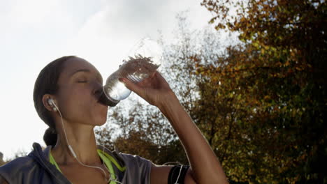 Runner-woman-drinking-water-bottle-sun-flare-solar-energy