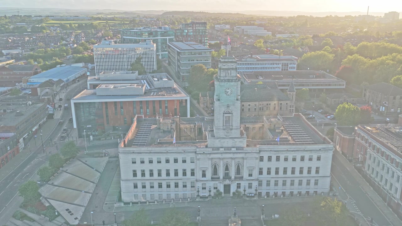 Radnice Barnsley dominuje centru města Barnsley, Jižní Yorkshire, Anglie. Úvodní záběr dronem nad občanskou čtvrtí Church Street, oblastí přestavby The Glass Works, při západu slunce ve zlaté hodince.