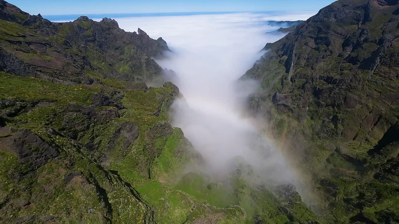 깊은 계곡을 가로지르는 무지개, 마데라의 초록색 절벽 사이에 구름 속에 숨겨져 있다.